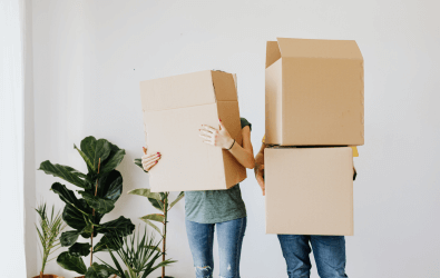 Two unidentifable people carrying moving boxes