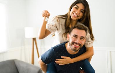 Man and woman showing their new home keys after buying a house